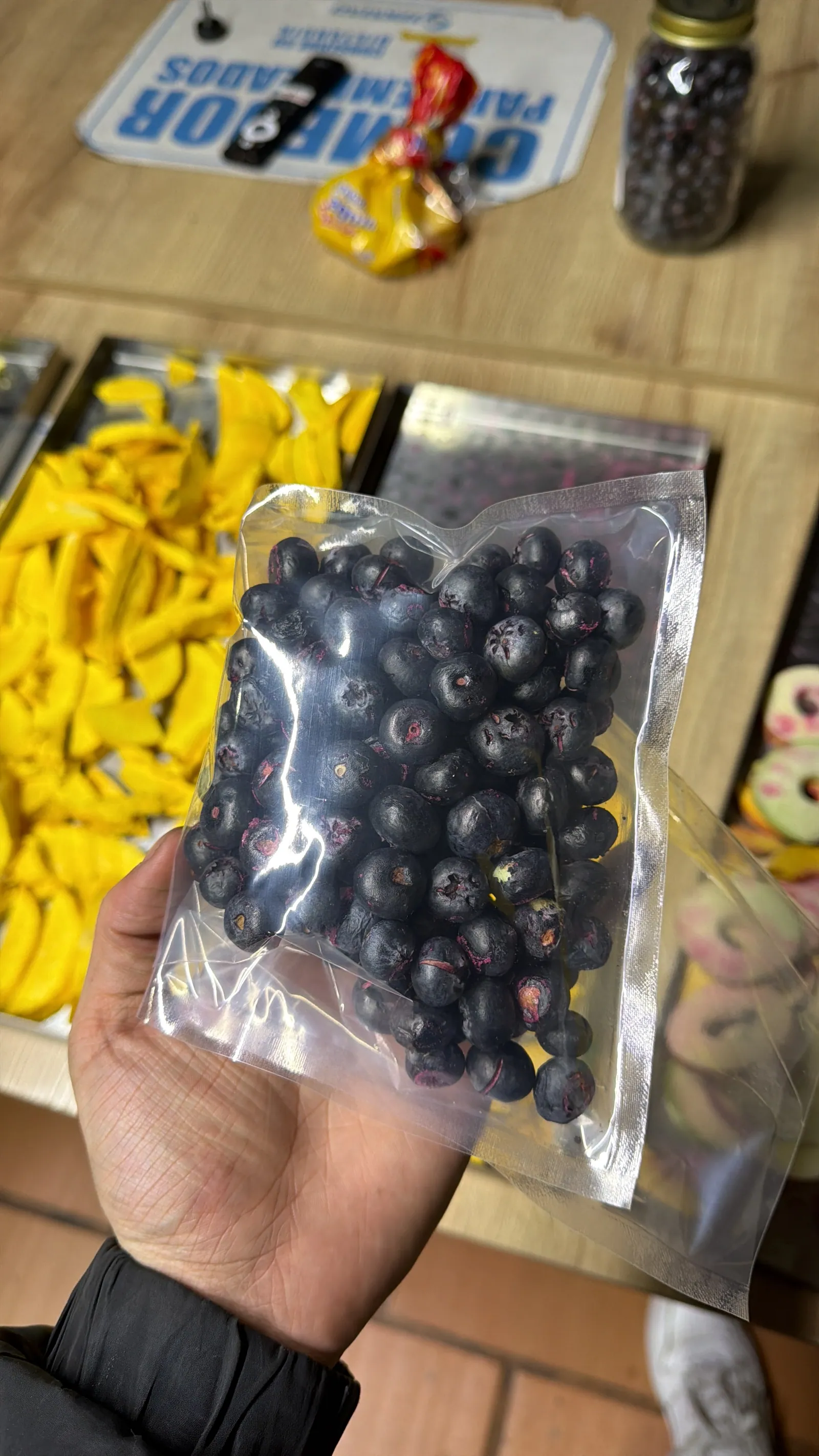 Bolsa de arándanos crocantes recién empacada, con bandejas de mango detrás
